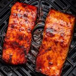 Two date glazed salmon filets in an air fryer basket.