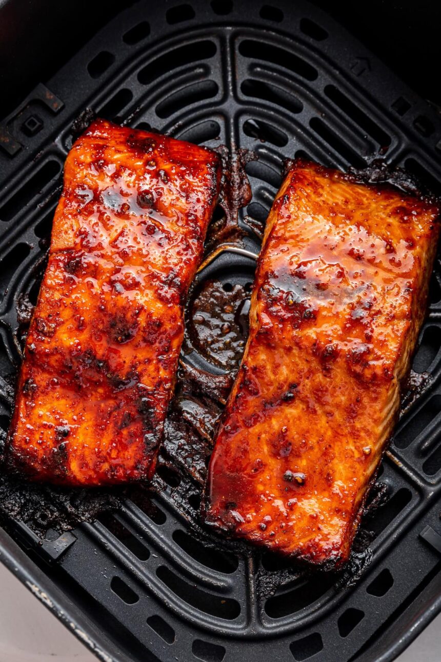 Two date glazed salmon filets in an air fryer basket.