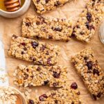 Multiple granola bars with dried cranberries and chocolate chips on parchment paper.