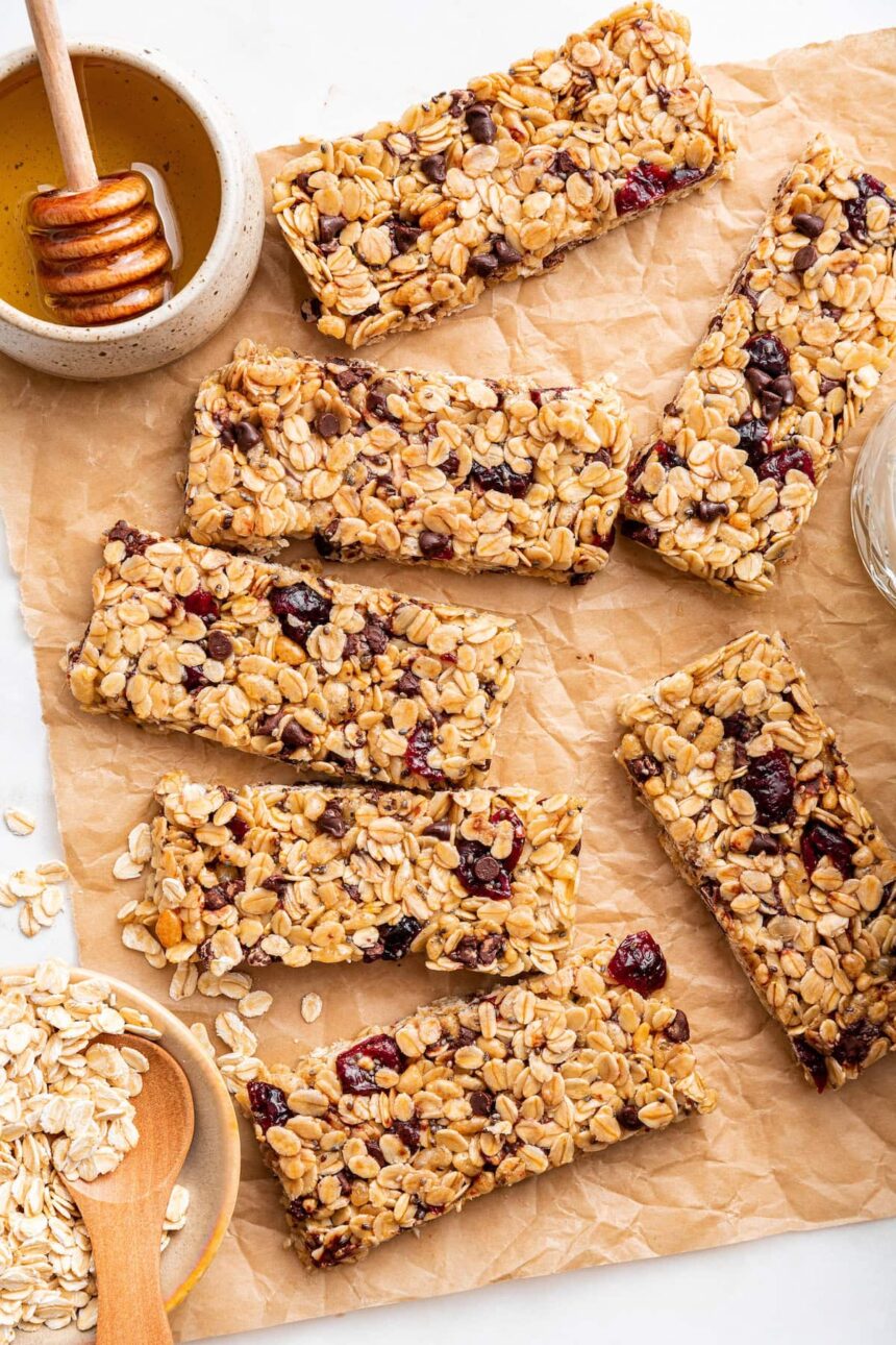 Multiple granola bars with dried cranberries and chocolate chips on parchment paper.