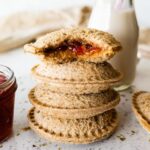 Four peanut butter uncrustables stacked on one another with the top having a bite taken from it.