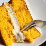 A slice of pumpkin cake with a fork taking a bite