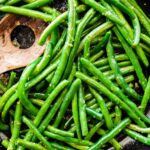 Sautéed Green Beans in a skillet with a wooden spatula.