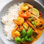 A serving of coconut shrimp curry with white rice in a small bowl.