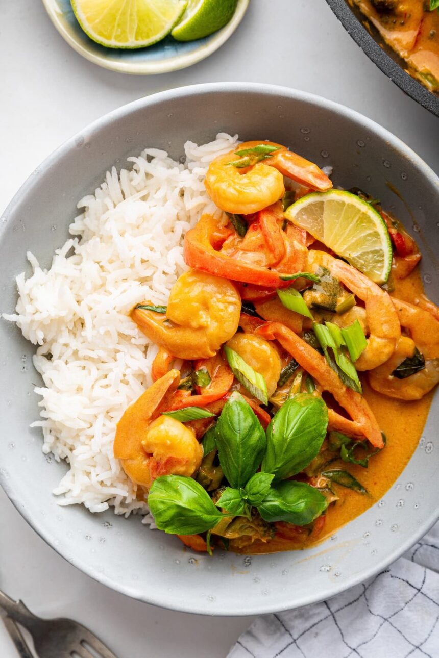 A serving of coconut shrimp curry with white rice in a small bowl.