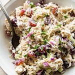 A sonoma chicken salad in a large bowl with ingredients like grapes, shredded chicken, pecans, and more.