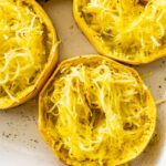 Roasted spaghetti squash rings in a white baking dish. The rings are shredded into long strands.