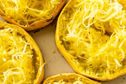 Roasted spaghetti squash rings in a white baking dish. The rings are shredded into long strands.