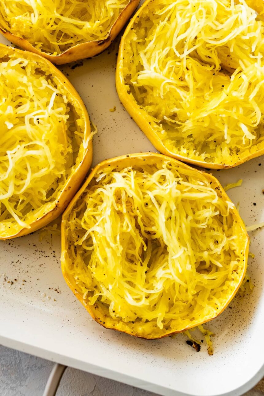 Roasted spaghetti squash rings in a white baking dish. The rings are shredded into long strands.