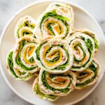 Multiple turkey pinwheel sandwiches on a plate.