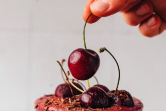 Placing a cherry on top of a glass filled with our chocolate cherry protein shake recipe