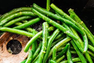 Saut&eacute;ed Green Beans in a skillet with a wooden spatula.