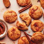 Overhead photo of apple butter snickerdoodle cookies next to cinnamon sticks, ground cinnamon, and apple butter