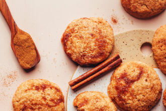 Overhead photo of apple butter snickerdoodle cookies next to cinnamon sticks, ground cinnamon, and apple butter