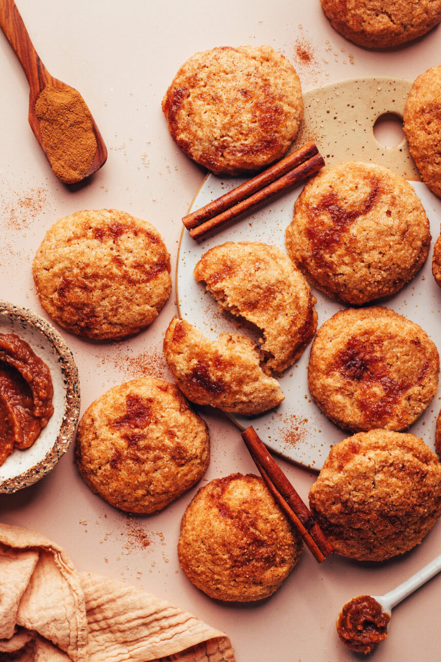 Overhead photo of apple butter snickerdoodle cookies next to cinnamon sticks, ground cinnamon, and apple butter