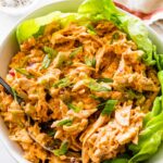 A bowl with buffalo chicken salad on a bed of lettuce.