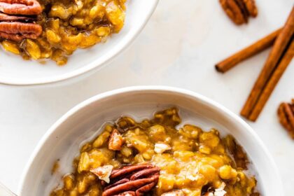 A bowl of pumpkin oatmeal with milk, and topped with pecans.