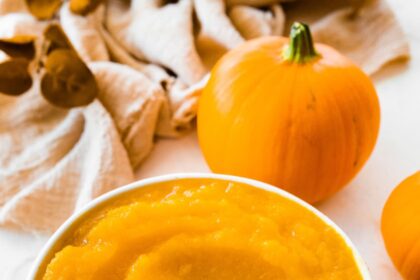 A homemade pumpkin puree in a bowl on a circular wooden board.