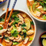 Two bowls of our cozy Thai-inspired curry noodle soup — one with chicken and one with tofu