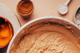 Using an electric mixer in a bowl of vegan pumpkin spice frosting