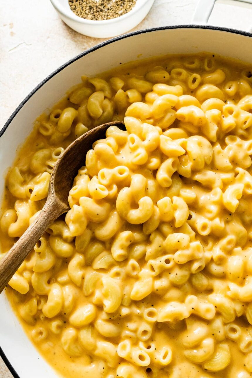 A large pot of cottage cheese mac and cheese with a wooden serving spoon.