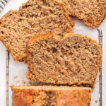 Oat flour banana bread on a cooling wire rack with three slices near the loaf.