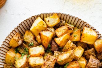 Roasted potatoes garnished with fresh parsley in a bowl.