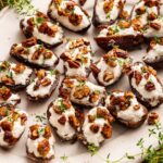 A large plate of multiple dates that are stuffed with goat cheese and topped with chopped pecans and fresh thyme.