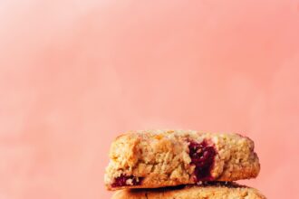 Stack of vegan gluten-free cranberry orange scones next to orange slices and cranberries