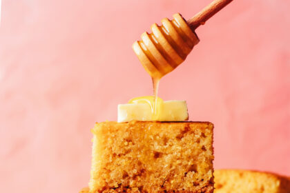 Drizzling honey onto a stack of gluten-free cornbread slices topped with butter