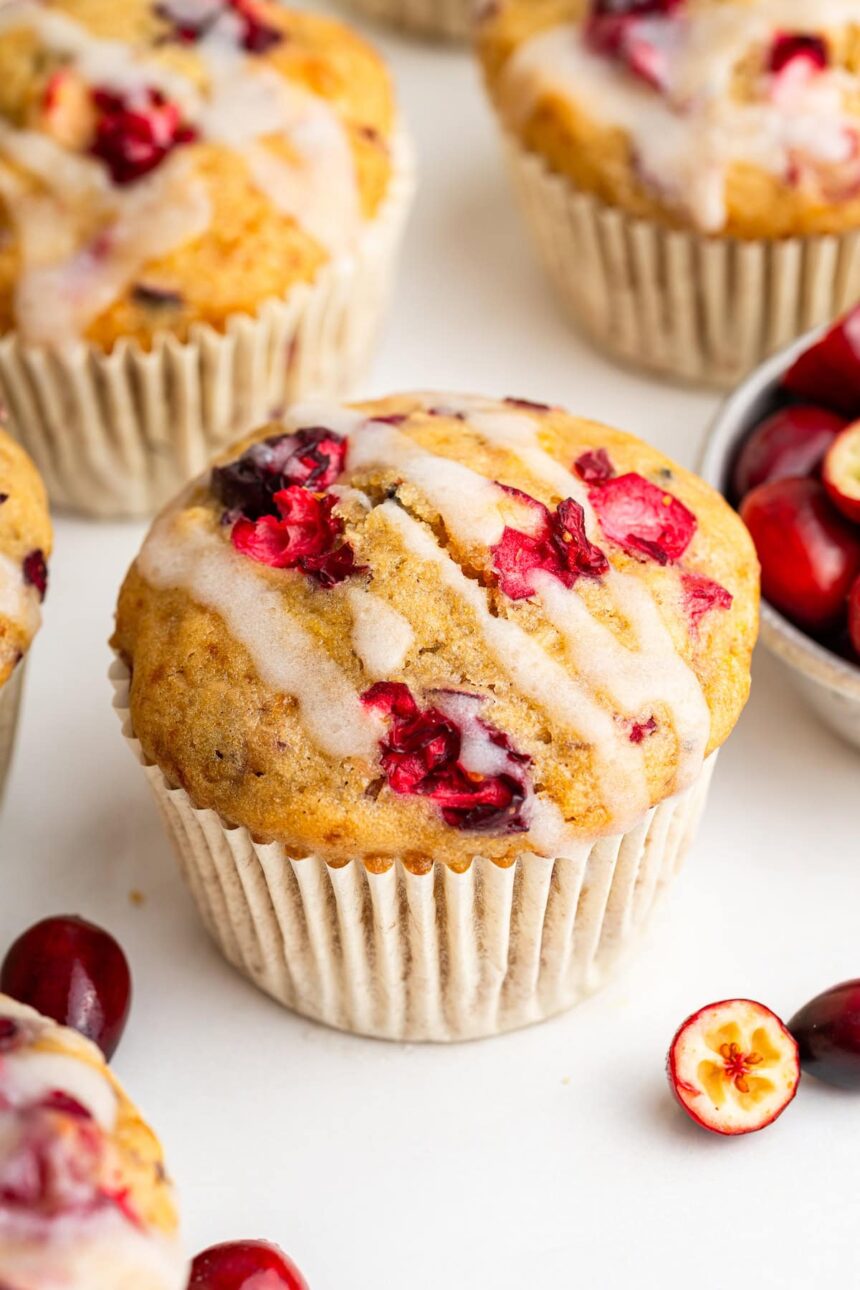 A cranberry orange muffin topped with a drizzle of an almond milk based glaze.