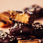 Close up shot of a stack of chocolate sea salt caramels with the top one partially eaten to show the soft, tender texture