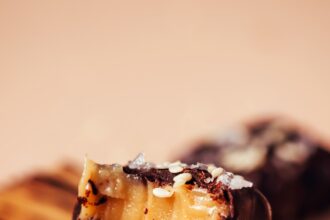 Close up shot of a stack of chocolate sea salt caramels with the top one partially eaten to show the soft, tender texture