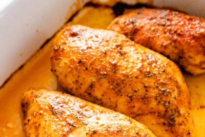 Four baked chicken breasts in a large baking dish.