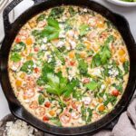 An egg white frittata in a cast iron skillet. The frittata is garnished with fresh herbs and feta cheese.