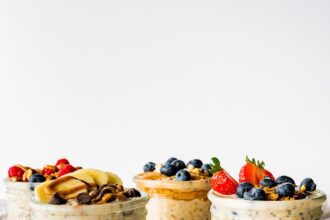 Four glass jars of overnight oats topped with fresh berries.