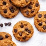 9 flourless peanut butter cookies with chocolate chips spread out on parchment paper.