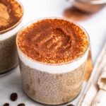 A glass cup of tiramisu chia pudding topped with cocoa powder.