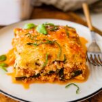 A serving of vegetarian tofu lasagna made with zucchini noodles on a white plate with a fork.