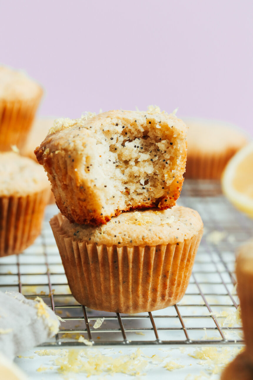 Stack of vegan gluten-free lemon poppy seed muffins with the inner texture showing where a bite was taken out of one muffin