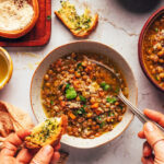 Bowls of Italian lentil soup with slices of garlic bread