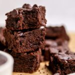 Three protein brownies stacked on top of one another. The top brownie has a bite taken out of it.