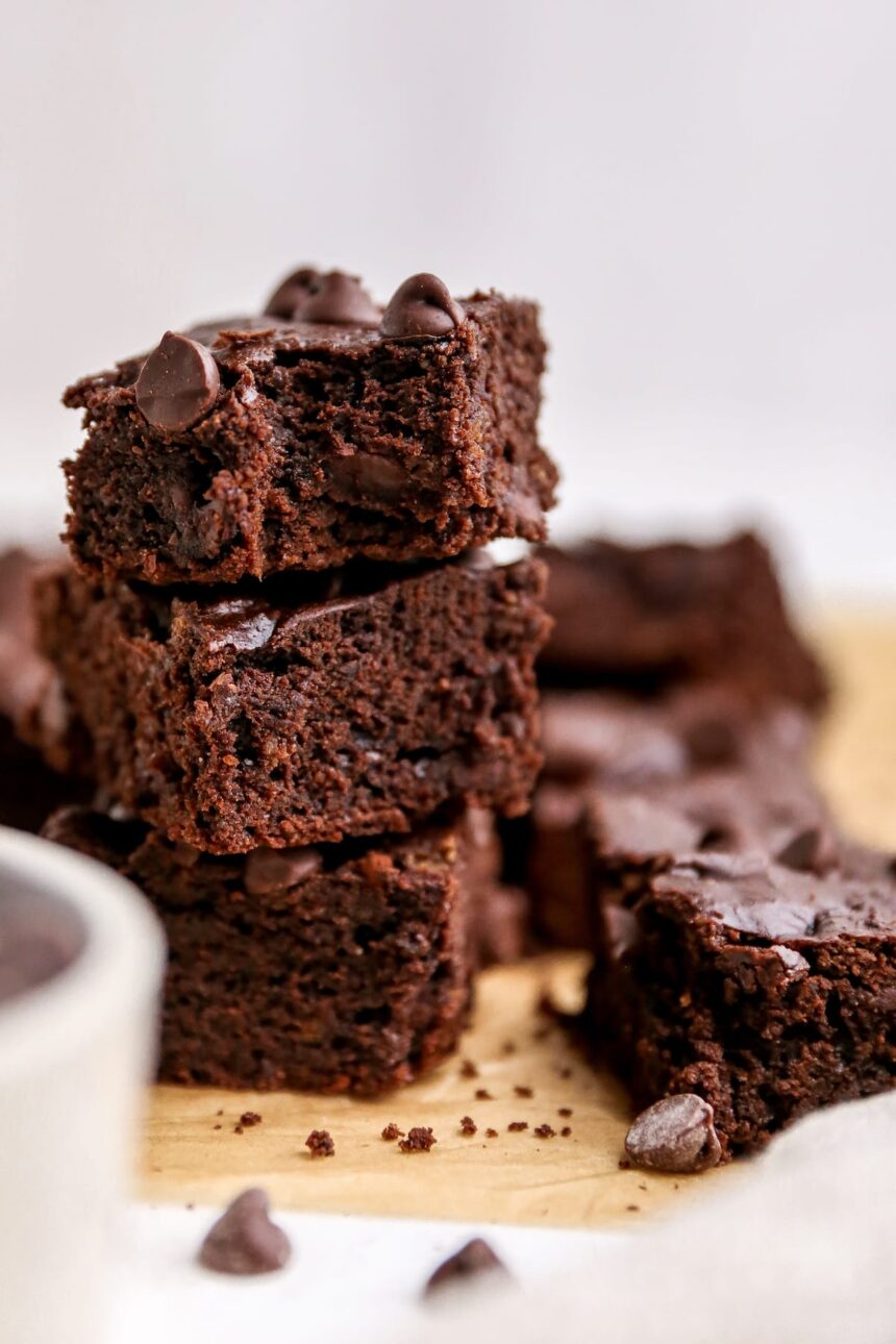 Three protein brownies stacked on top of one another. The top brownie has a bite taken out of it.