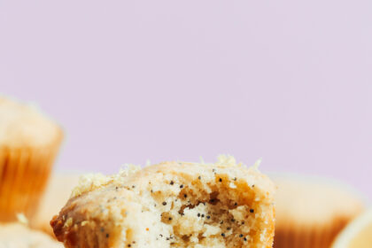 Stack of vegan gluten-free lemon poppy seed muffins with the inner texture showing where a bite was taken out of one muffin