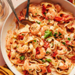 Serving spoons resting in a skillet of our dairy-free Tuscan shrimp pasta recipe