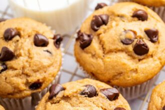 Kodiak cake muffins with chocolate chips on top, cooling on a wire rack.