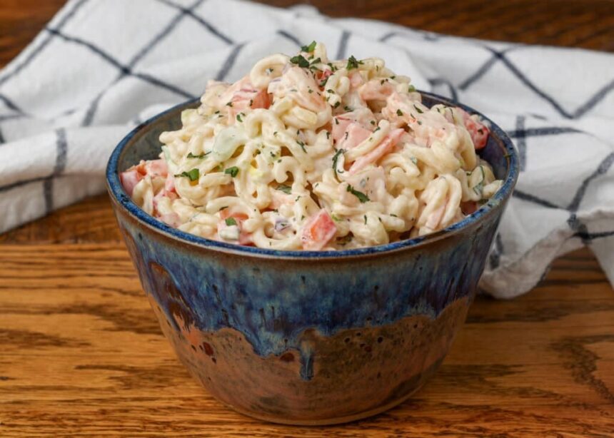 shrimp pasta salad in a pottery bowl with a white and blue patterned linen