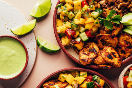 Drizzling green tahini sauce onto a Jerk Tofu & Roasted Plantain Bowl