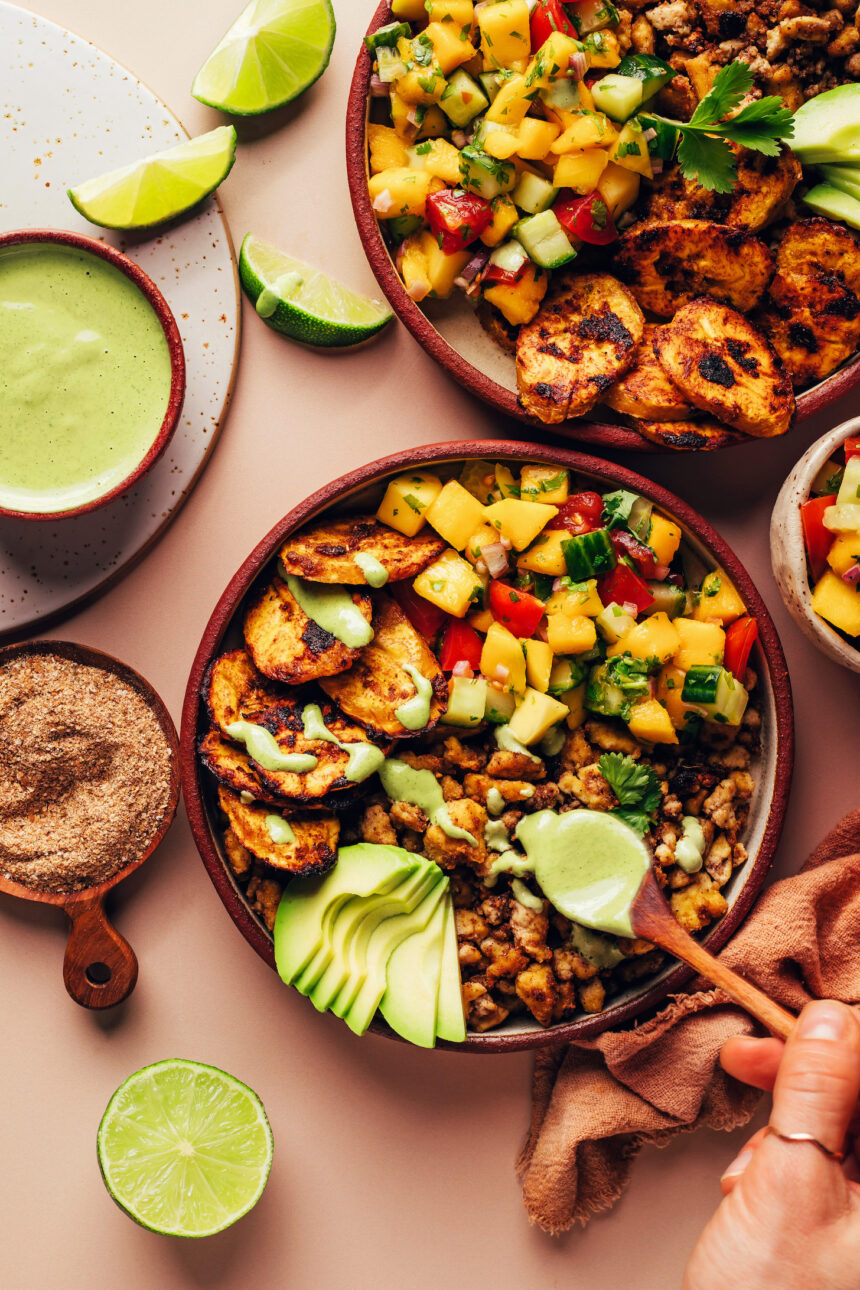 Drizzling green tahini sauce onto a Jerk Tofu & Roasted Plantain Bowl