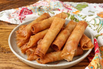 pottery plate stacked with lumpia next to napkin on table